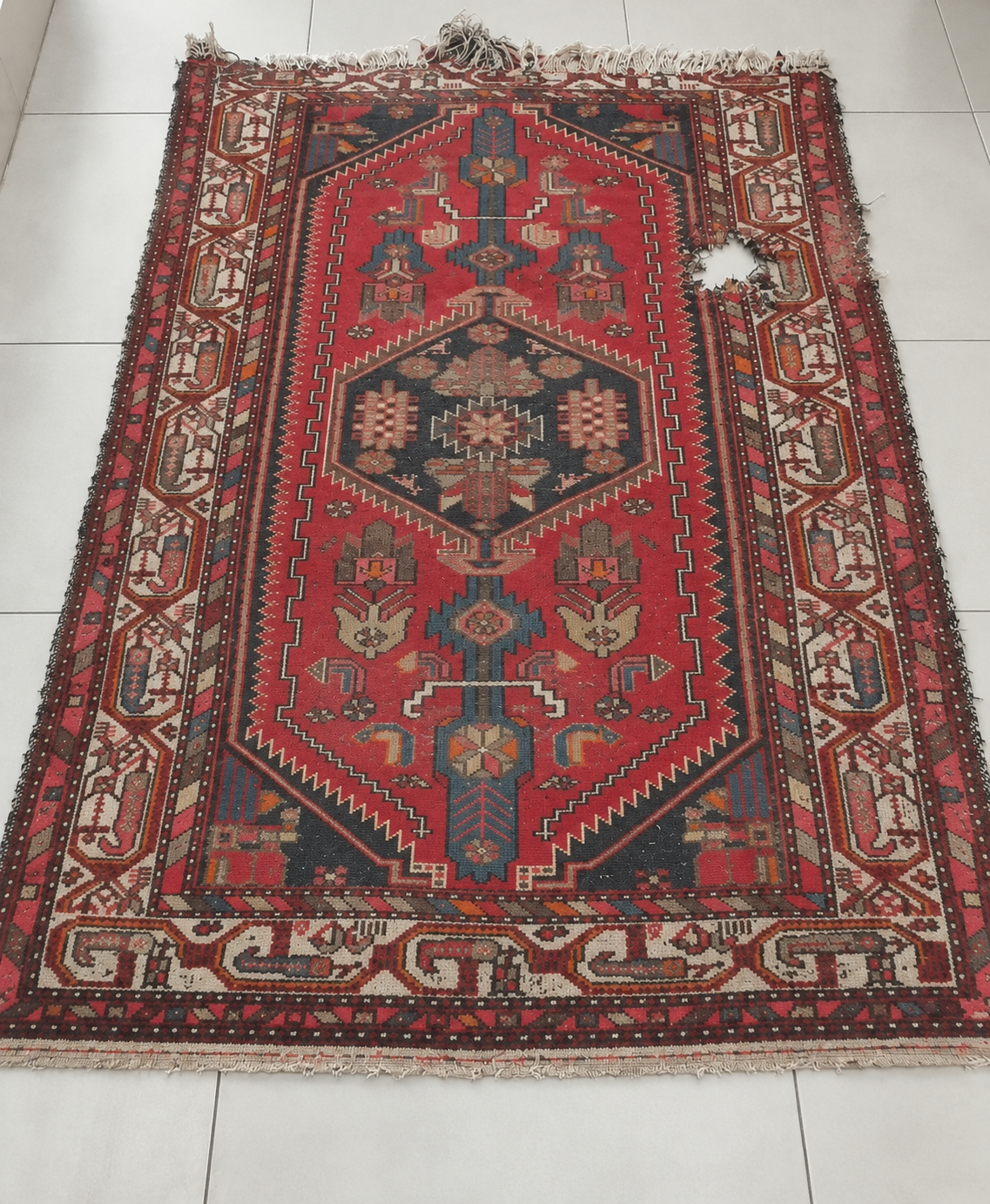 Damaged Persian carpet showing a hole requiring repair