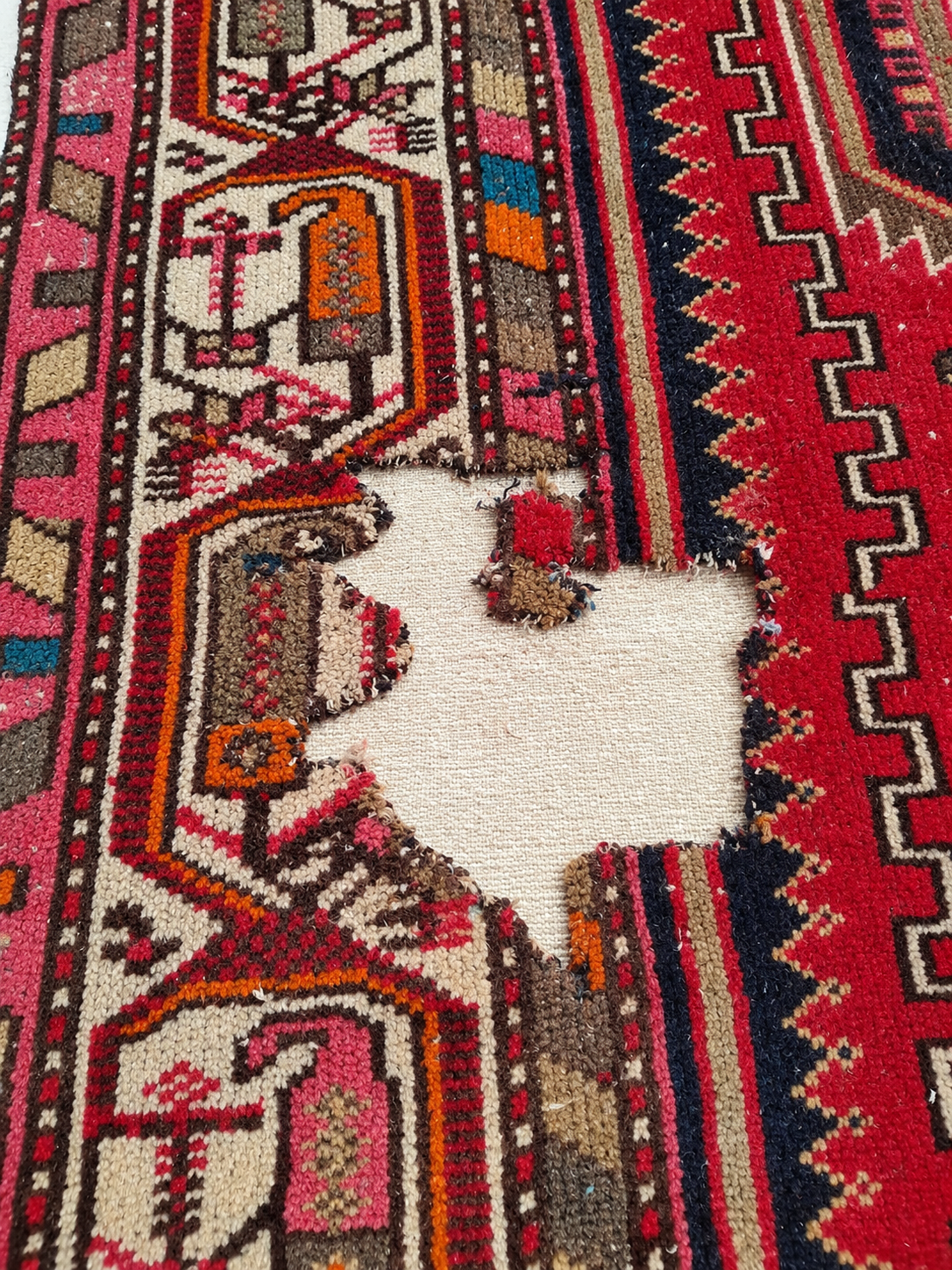 Close-up of damage on a Persian carpet showing fine detail