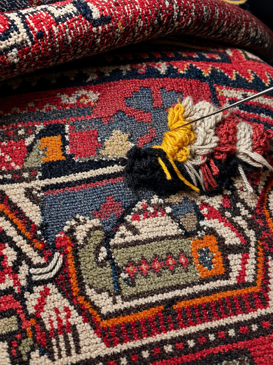 Persian carpet being repaired by hand with stitching and reweaving